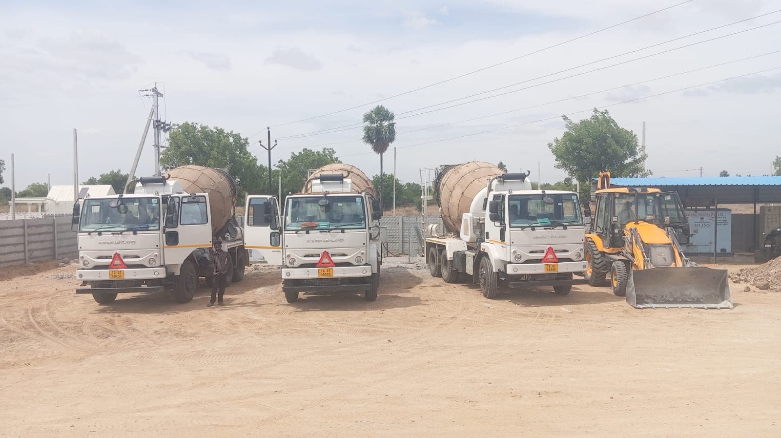 Fleet of transit mixers and a backhoe loader at the plant yard